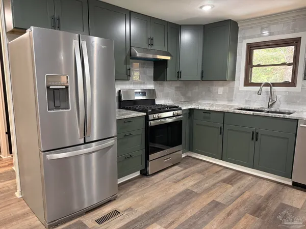 a kitchen with stainless steel appliances granite countertop a refrigerator sink and stove