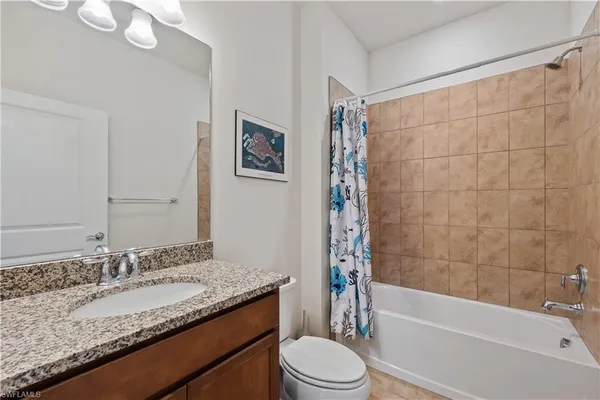 a bathroom with a granite countertop sink a toilet and bathtub