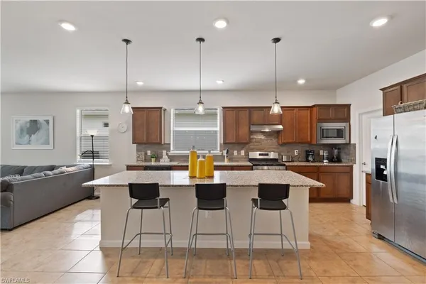 a kitchen with stainless steel appliances kitchen island granite countertop a refrigerator a stove a kitchen island a dining table and chairs
