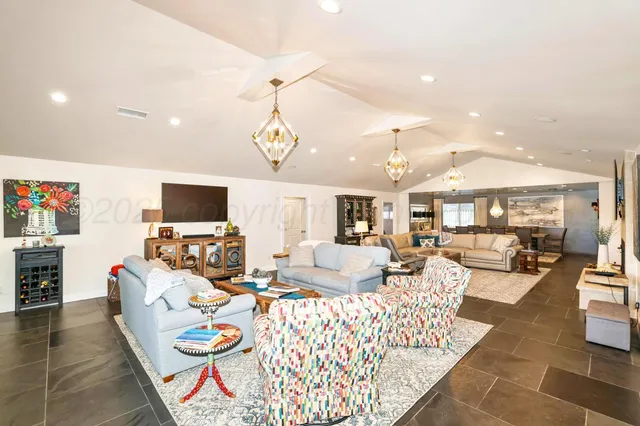 a living room with furniture dining table a rug and a chandelier