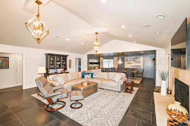 a living room with stainless steel appliances furniture a flat screen tv and a kitchen view