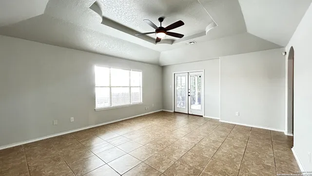 a view of n empty room with a ceiling fan and window