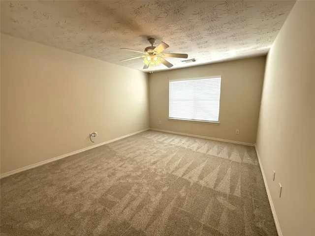 an empty room with a chandelier fan and windows
