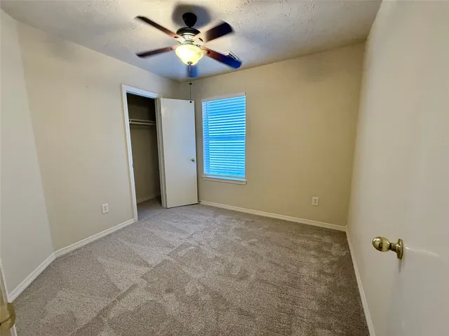 an empty room with a ceiling fan and a window