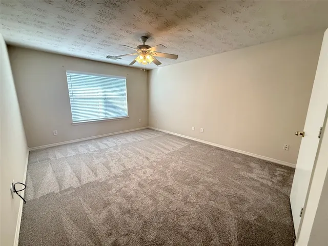 en empty room with windows and chandelier fan