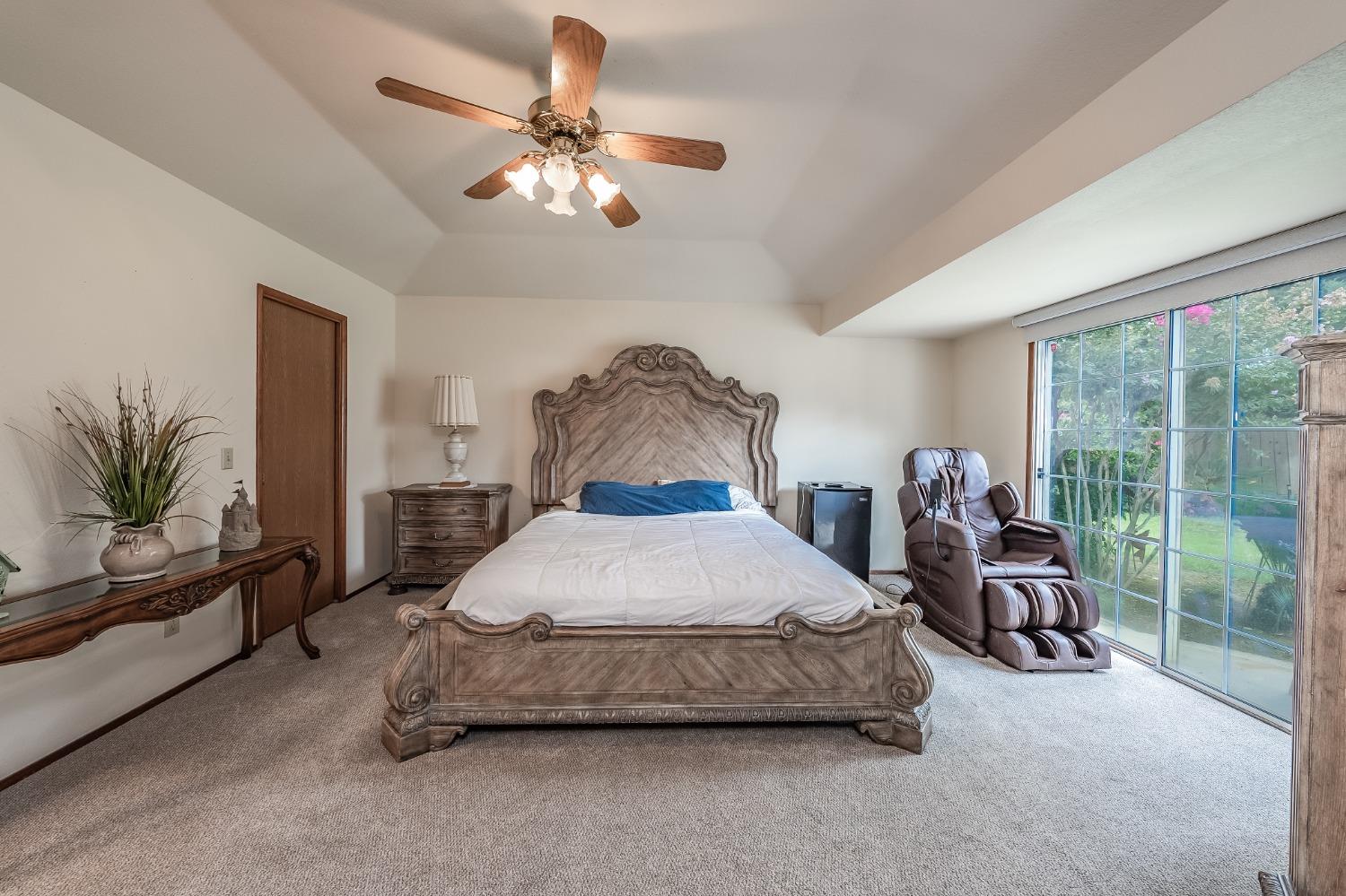 2370 Jonathan Way Madera, CA 93637 - Photo 19 of 41 a bedroom with a bed a chandelier and a large window