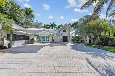 a front view of a house with a yard and palm trees