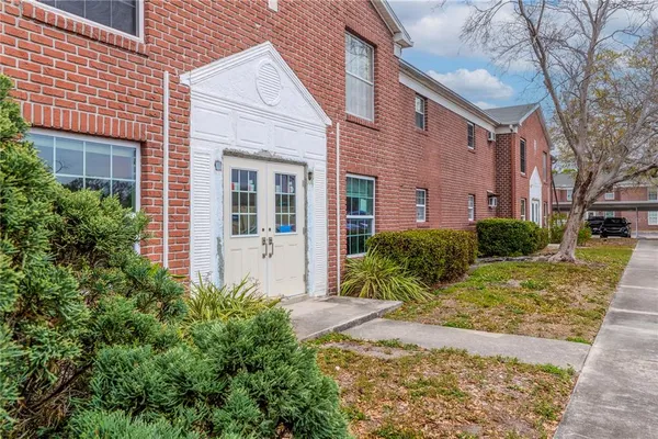 a view of a house with brick walls plants and large tree