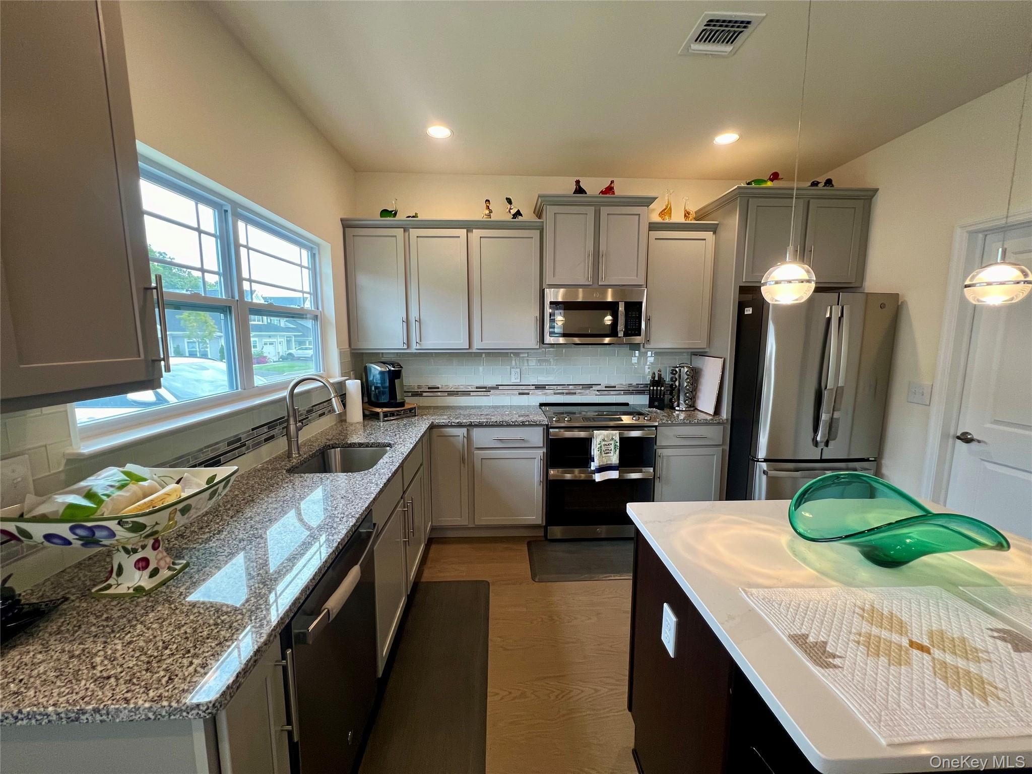 37 Willow Circle, Unit 37 Coram, NY 11727 - Photo 11 of 18 a kitchen with kitchen island granite countertop a sink a counter top space stainless steel appliances cabinets and a counter top space