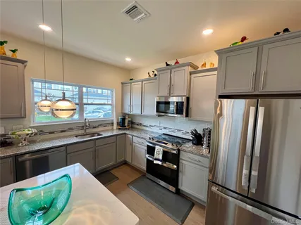 a kitchen with kitchen island granite countertop a sink a counter top space stainless steel appliances cabinets and a counter top space