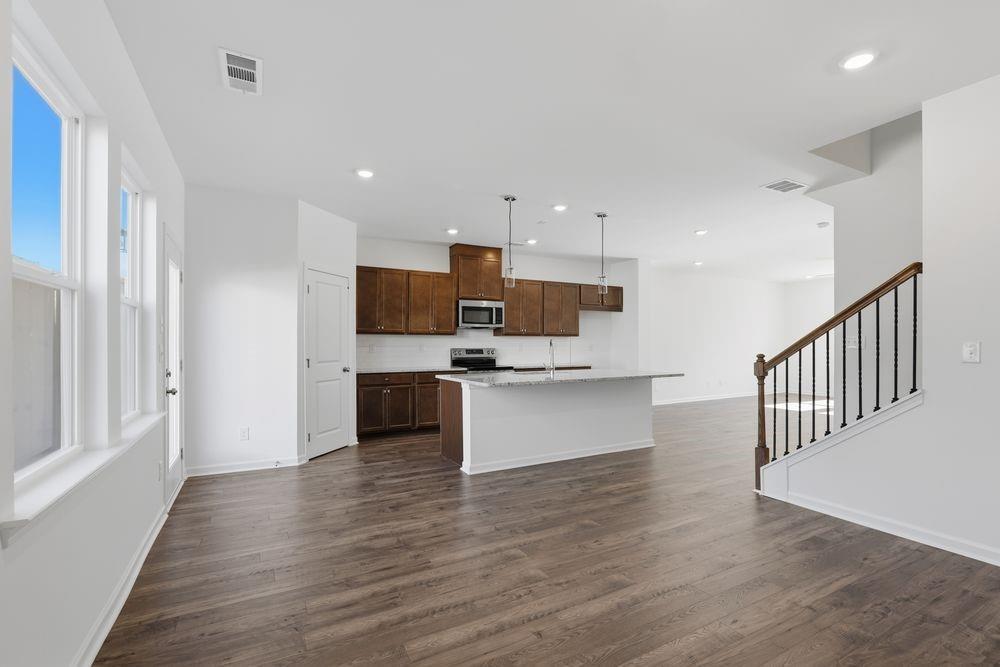 6121 Wayburn Street Tucker, GA 30084 - Photo 15 of 47 a kitchen with stainless steel appliances kitchen island wooden floors and white cabinets