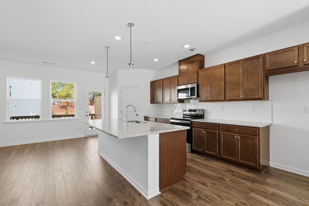 6121 Wayburn Street Tucker, GA 30084 - Photo 7 of 47 a kitchen with stainless steel appliances granite countertop wooden cabinets a stove top oven a sink and dishwasher with wooden floor