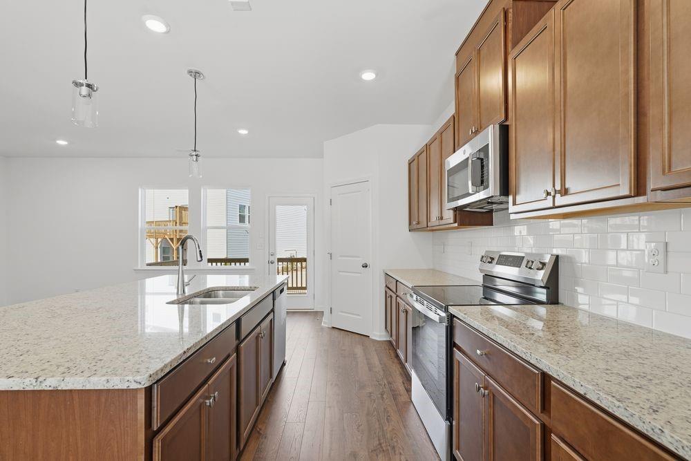 6121 Wayburn Street Tucker, GA 30084 - Photo 8 of 47 a kitchen with stainless steel appliances granite countertop lots of counter top space a sink a stove and a wooden floors