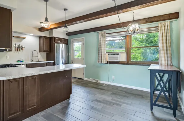 a kitchen with stainless steel appliances granite countertop a refrigerator a stove a sink and white cabinets with wooden floor