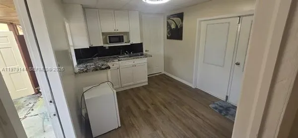 a kitchen with a refrigerator a stove top oven and wooden floor