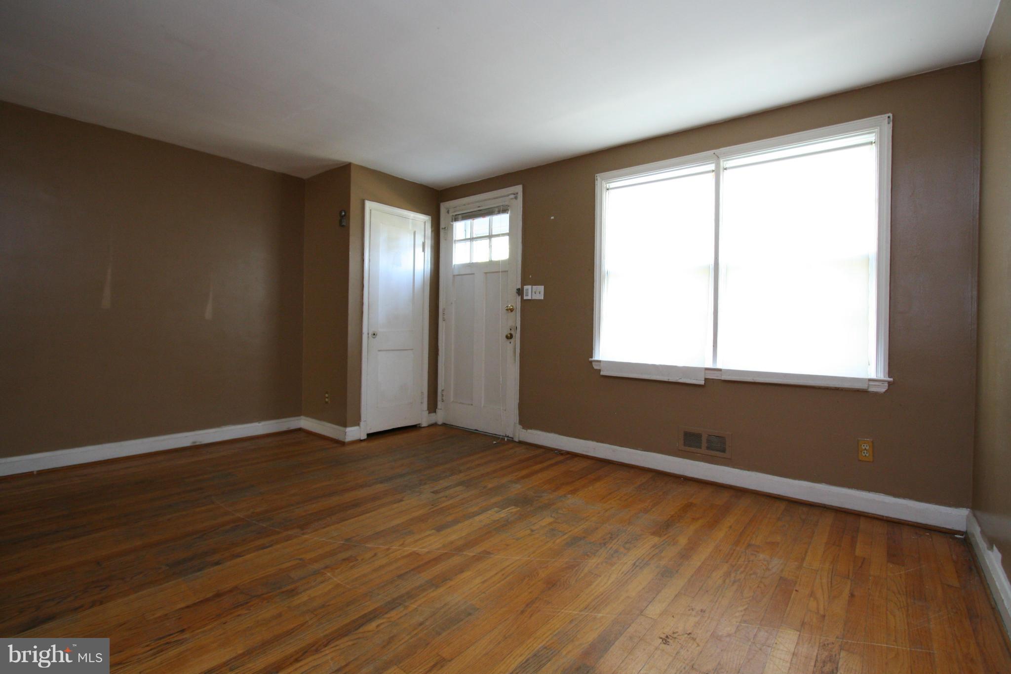 4407 Cedar Garden Road Baltimore, MD 21229 - Photo 4 of 30 a view of an empty room with wooden floor and a window