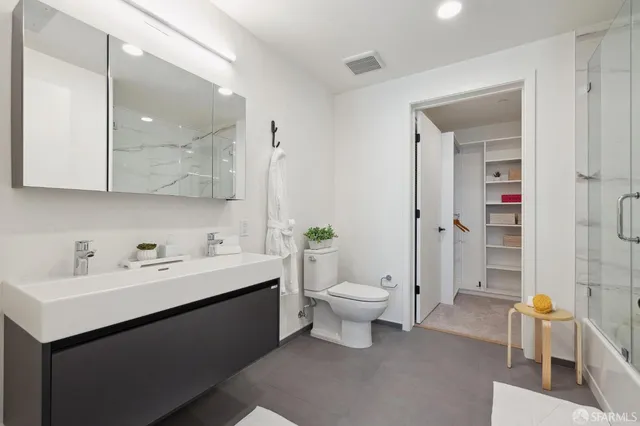 a bathroom with a toilet sink double vanity and mirror