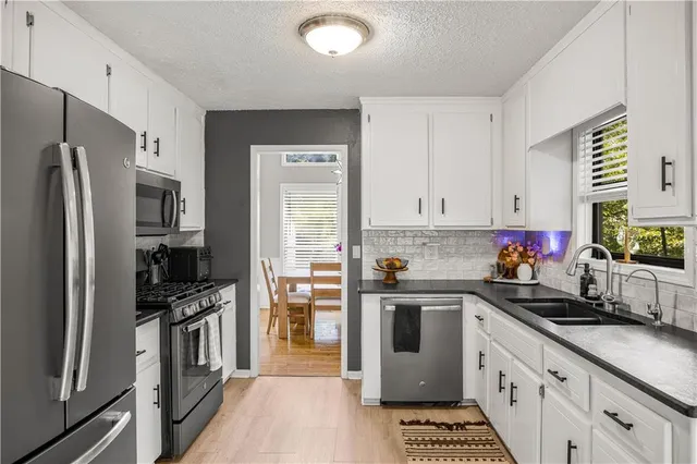 a kitchen with stainless steel appliances a refrigerator sink and white cabinets