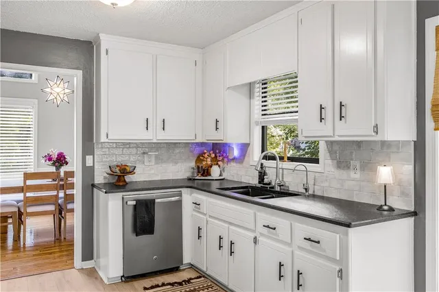 a kitchen with stainless steel appliances granite countertop a sink dishwasher a stove and a refrigerator