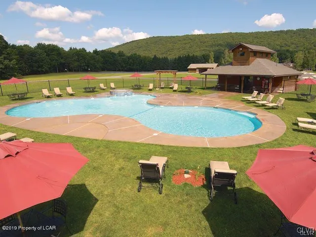 a view of a swimming pool with lawn chairs under an umbrella