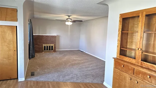 an empty room with fireplace cabinet and windows