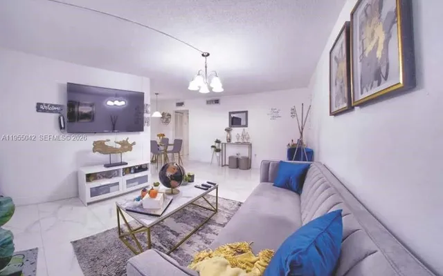 a living room with furniture a chandelier and a flat screen tv