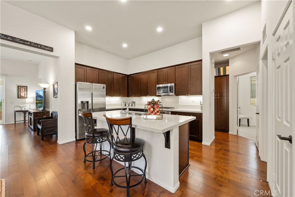 26519 Rim Creek Path Menifee, CA 92584 - Photo 19 of 45 a kitchen with stainless steel appliances a table chairs refrigerator and wooden floor