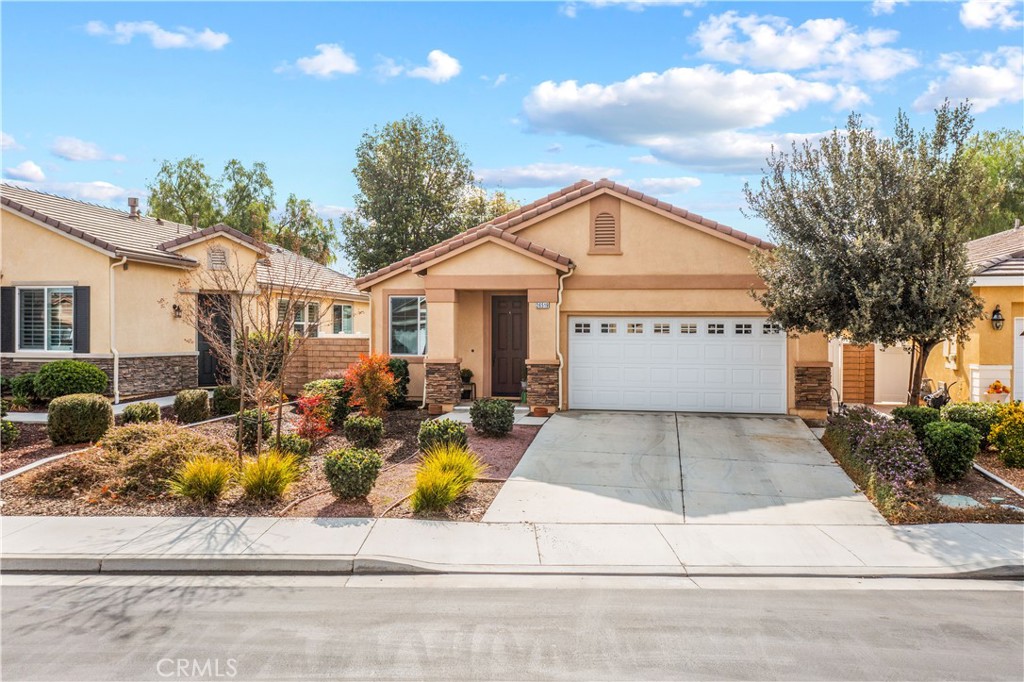 26519 Rim Creek Path Menifee, CA 92584 - Photo 2 of 45 a view of a white house with a fountain and a yard with plants