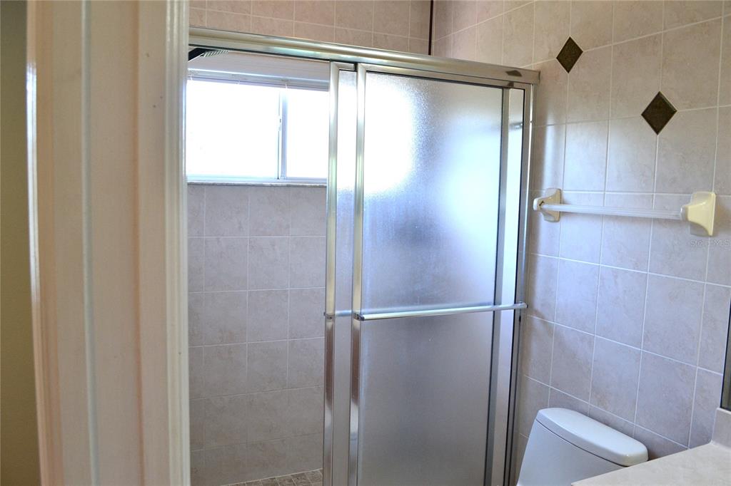 11235 Kapok Grand Circle Madeira Beach, FL 33708 - Photo 13 of 34 a bathroom with a glass shower door