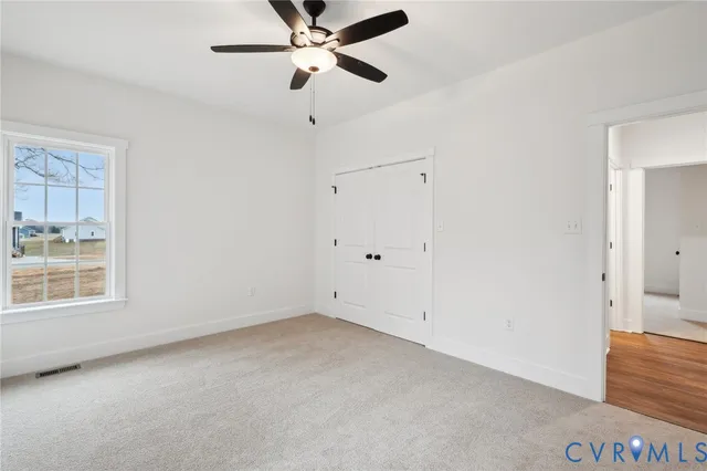 an empty room with a window and a fan