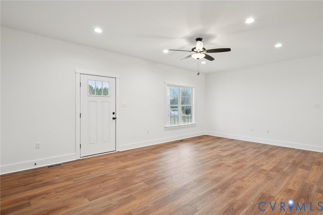 2090 Cartersville Road Cartersville, VA 23027 - Photo 5 of 35 an empty room with wooden floor ceiling fan & windows