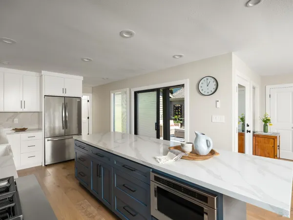 a large kitchen with kitchen island a large window a sink and stainless steel appliances