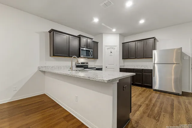 a kitchen with kitchen island a counter top space cabinets and stainless steel appliances