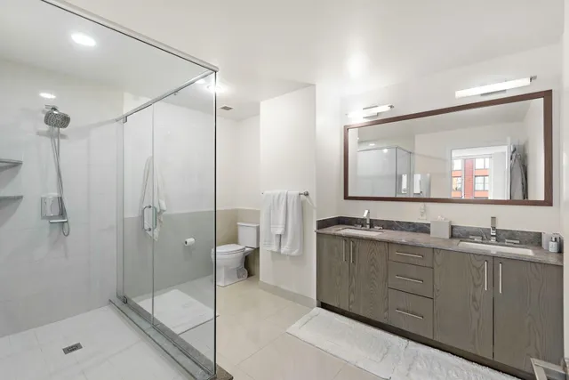 a spacious bathroom with a shower sink mirror and toilet