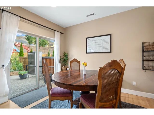a kitchen with stainless steel appliances kitchen island granite countertop a dining table chairs and a refrigerator