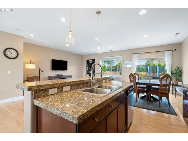 a kitchen with stainless steel appliances granite countertop a stove a refrigerator a sink a dining table and chairs