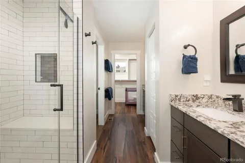 a bathroom with a granite countertop sink a mirror and shower