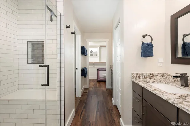 a bathroom with a granite countertop sink a mirror and shower