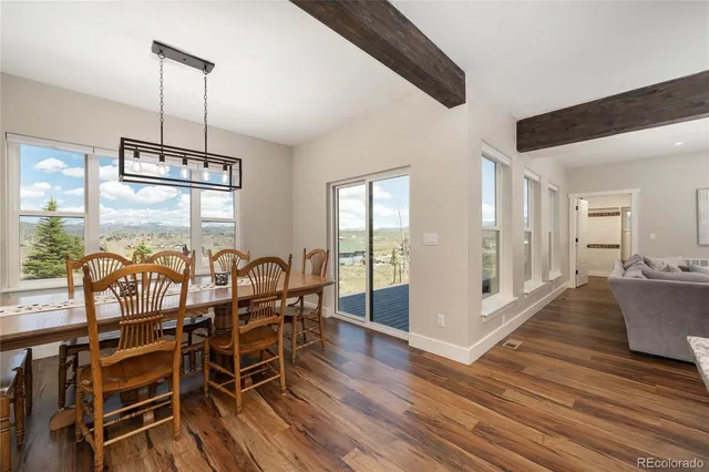 a dining room with wooden floor a chandelier a glass table and chairs