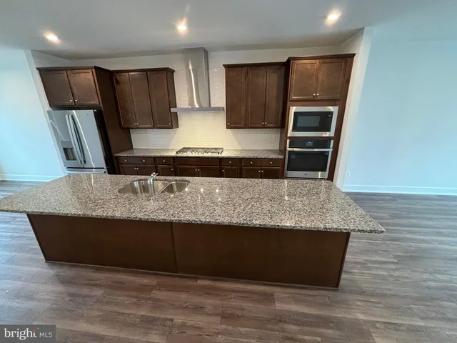 a kitchen with stainless steel appliances granite countertop a sink a stove a microwave and a refrigerator