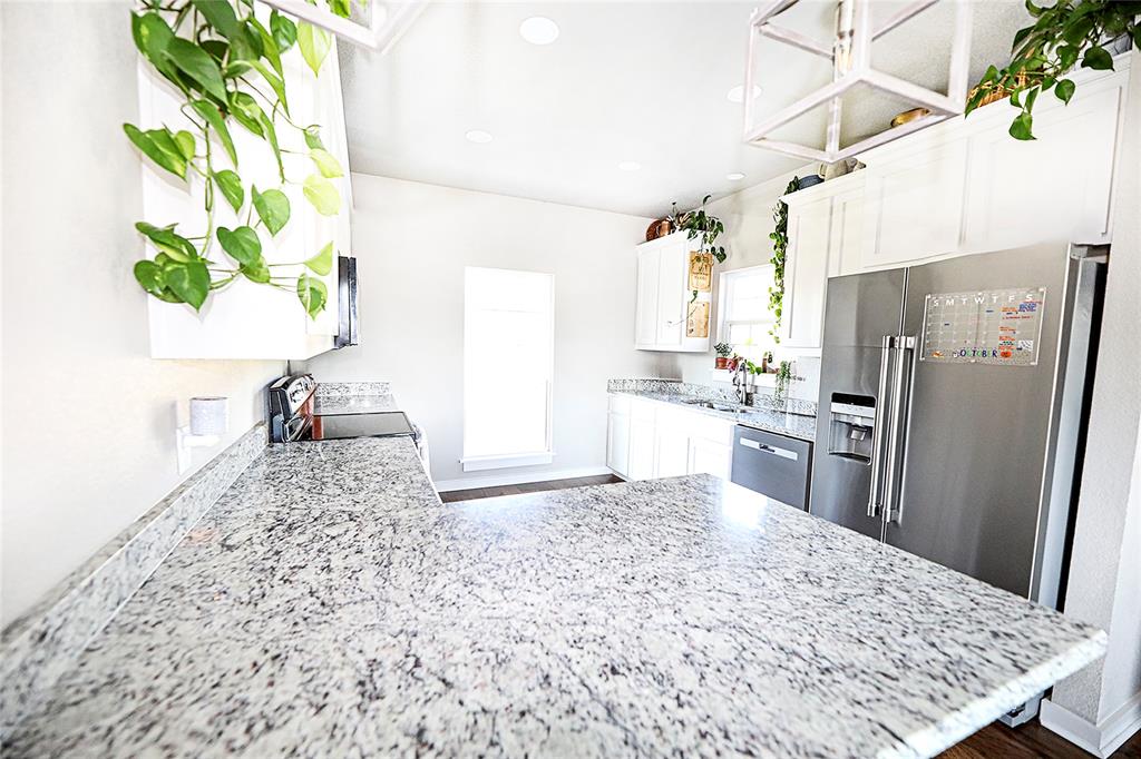 305 Main Street Nocona, TX 76255 - Photo 11 of 36 a kitchen with stainless steel appliances kitchen island granite countertop a refrigerator a stove a sink a counter space and a couch