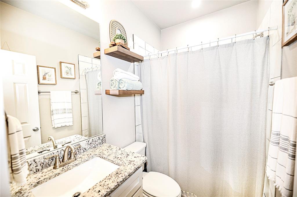 305 Main Street Nocona, TX 76255 - Photo 17 of 36 a bathroom with a granite countertop sink vanity mirror and a shower