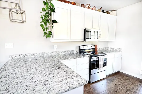a kitchen with granite countertop a stove a sink and a microwave