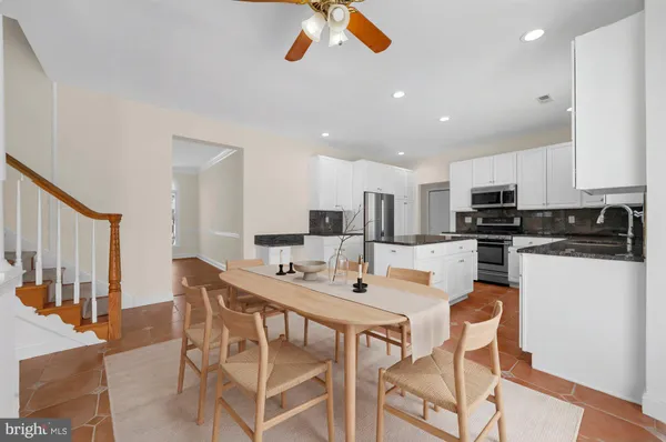 a kitchen with stainless steel appliances kitchen island granite countertop a dining table and chairs