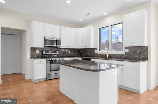 a kitchen with granite countertop white cabinets and stainless steel appliances