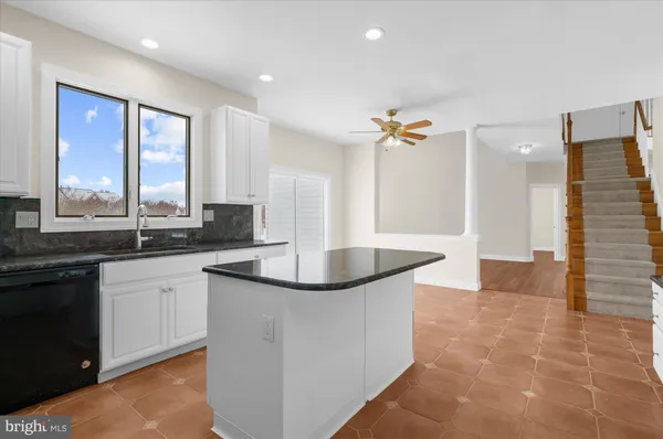 an empty room with wooden floor a ceiling fan a fireplace and windows