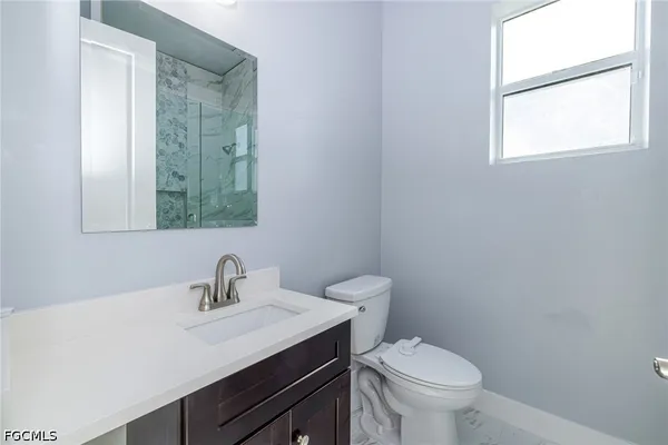 a bathroom with a toilet a sink a mirror and a window