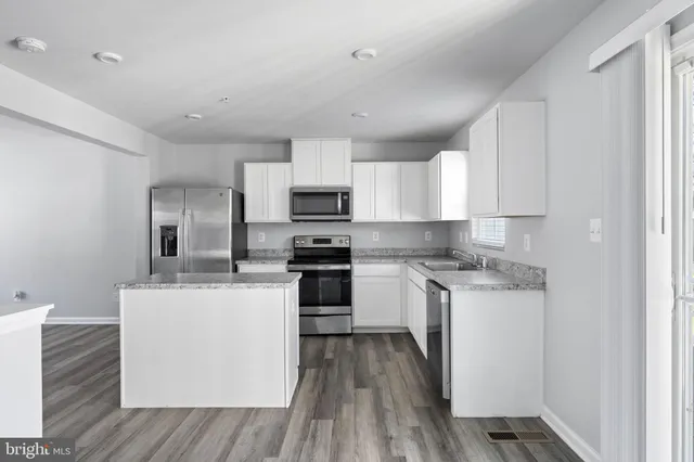 a kitchen with a sink a counter top space stainless steel appliances and cabinets