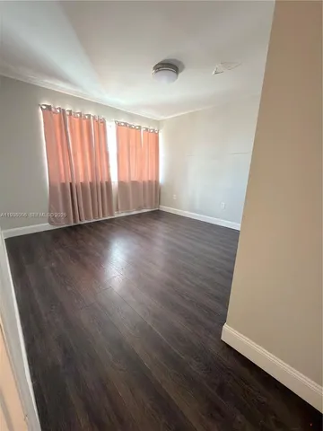 an empty room with wooden floor and entrance