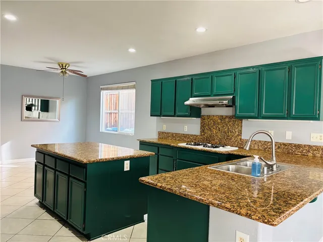 a kitchen with kitchen island granite countertop a sink a stove and a refrigerator